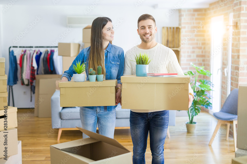 Young couple moving to a new home, smiling happy holding cardboard boxes at new apartment Young couple moving to a new home, smiling happy holding cardboard boxes at new apartment