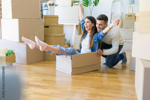 Young couple moving to a new home, having fun riding cardboard boxes © Krakenimages.com