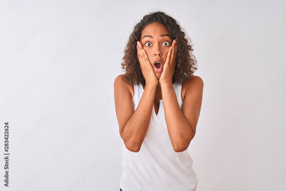 Young brazilian woman wearing casual t-shirt standing over isolated white background afraid and shocked, surprise and amazed expression with hands on face