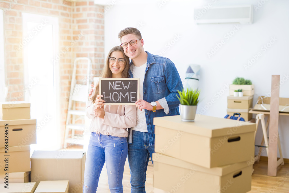Beautiful young couple hugging in love and holding blackboard moving to a new home, smiling happy for new apartment Beautiful young couple hugging in love and holding blackboard moving to a new home, smiling happy for new apartment