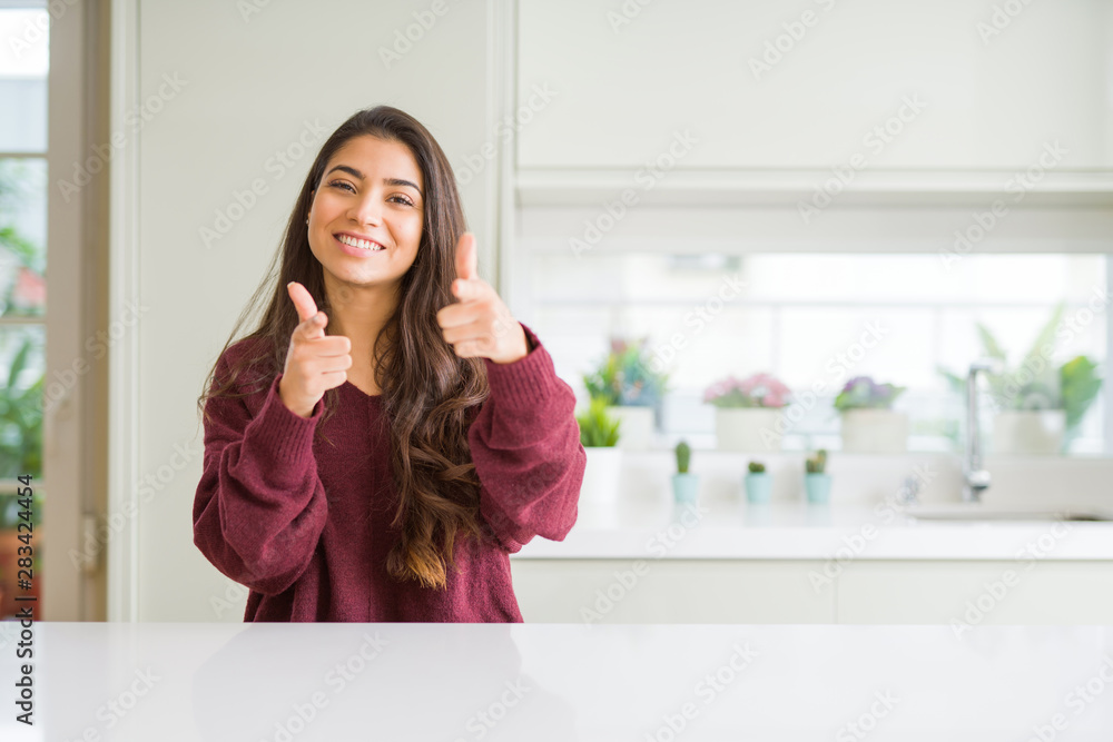 Young beautiful woman at home pointing fingers to camera with happy and funny face. Good energy and vibes. Young beautiful woman at home pointing fingers to camera with happy and funny face. Good energy and vibes.