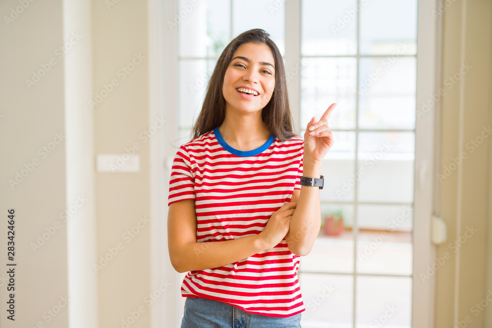 Young beautiful woman wearing casual t-shirt with a big smile on face, pointing with hand and finger to the side looking at the camera. Young beautiful woman wearing casual t-shirt with a big smile on face, pointing with hand and finger to the side looking at the camera.