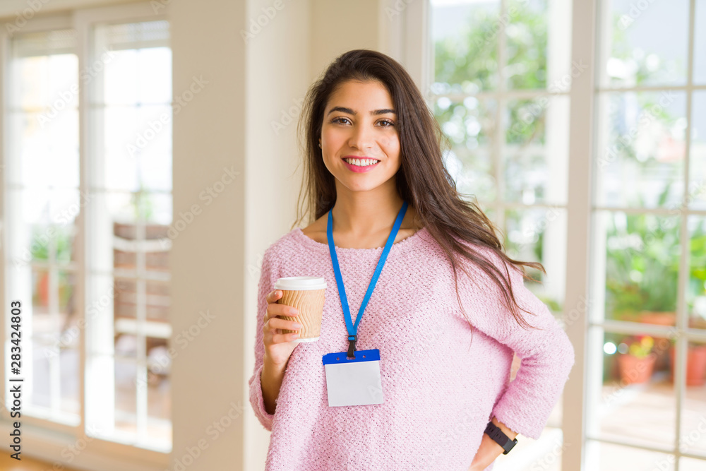 Young beautiful business woman wearing an id card drinking a cup of coffee Young beautiful business woman wearing an id card drinking a cup of coffee