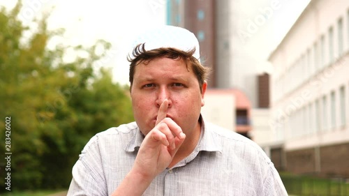 Muslim man making a shushing gesture raising his finger to his lips in a seductive gesture as he asks for silence photo