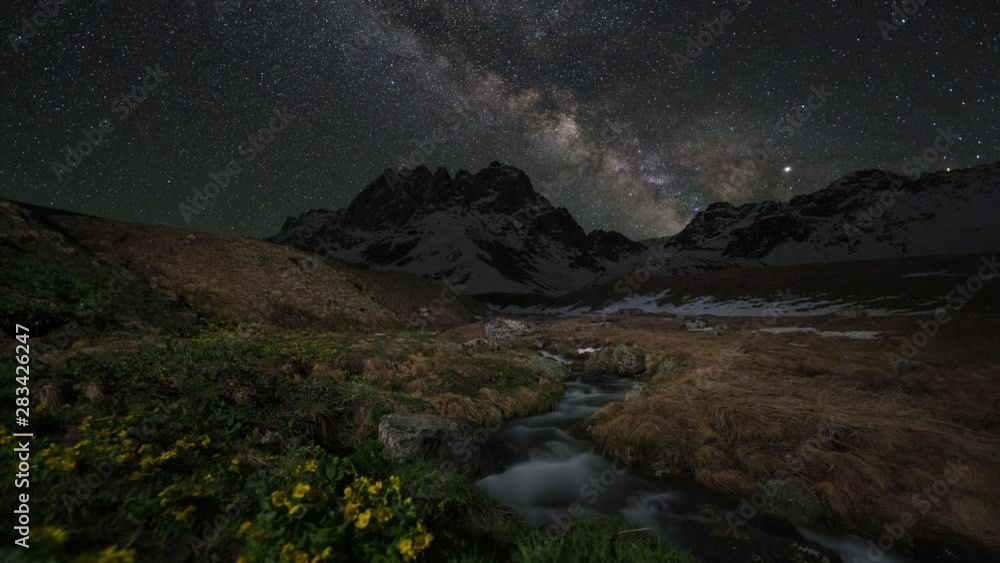 timelapse of milky way above the snow-capped mountains and creek timelapse of milky way above the snow-capped mountains and creek