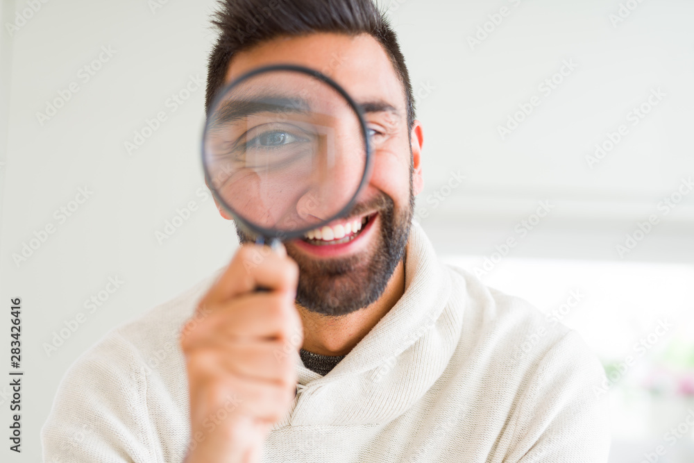 Handsome man using magnifying glass, doing funny faces Handsome man using magnifying glass, doing funny faces
