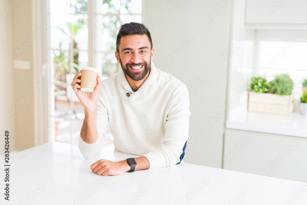 Handsome man smiling while enjoying drinking a take away coffee in the morning