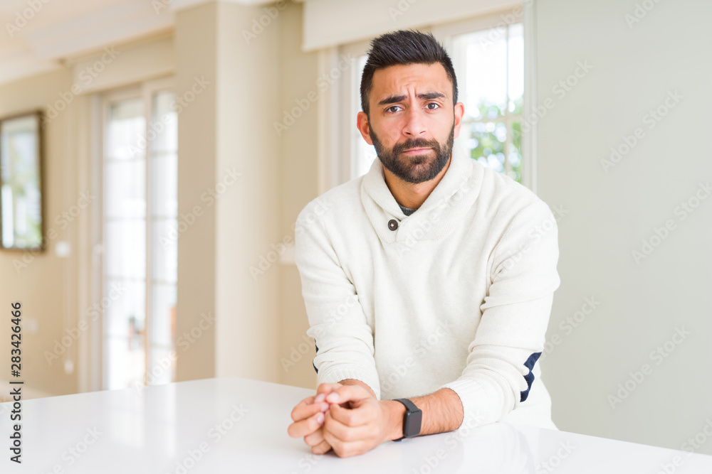 Handsome hispanic man wearing casual white sweater at home depressed and worry for distress, crying angry and afraid. Sad expression.