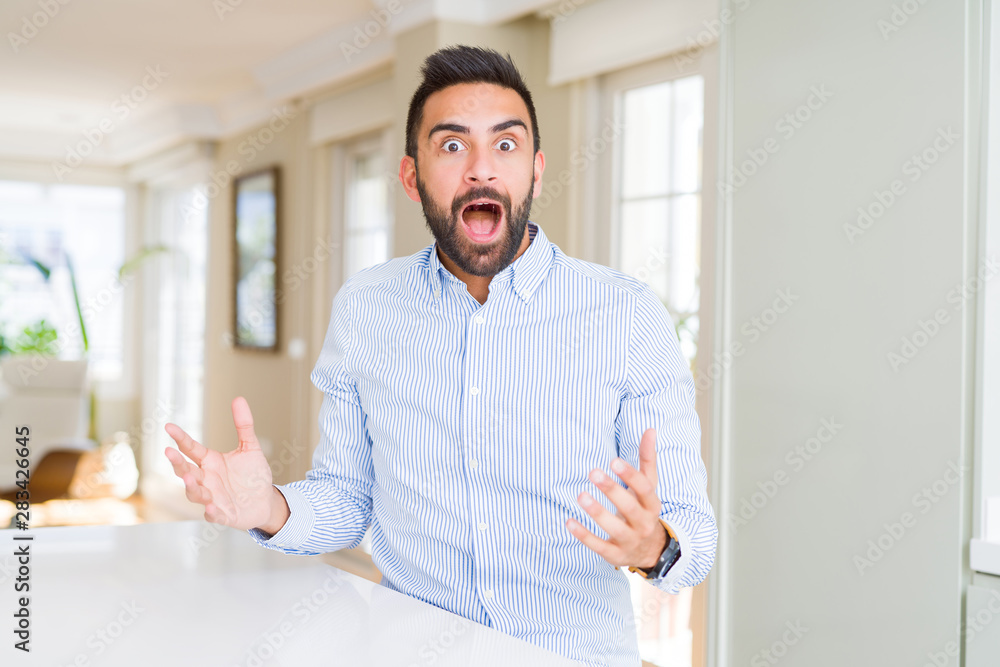 Fototapeta premium Handsome hispanic business man celebrating crazy and amazed for success with arms raised and open eyes screaming excited. Winner concept