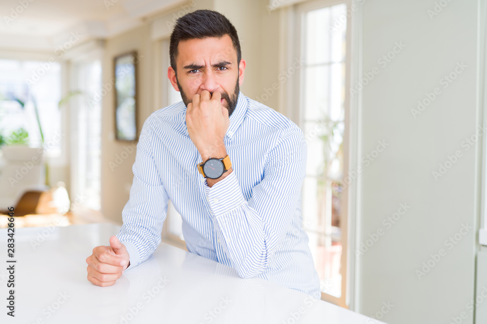 Handsome hispanic business man looking stressed and nervous with hands on mouth biting nails. Anxiety problem.