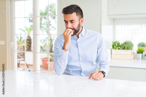 Handsome hispanic business man looking stressed and nervous with hands on mouth biting nails. Anxiety problem.