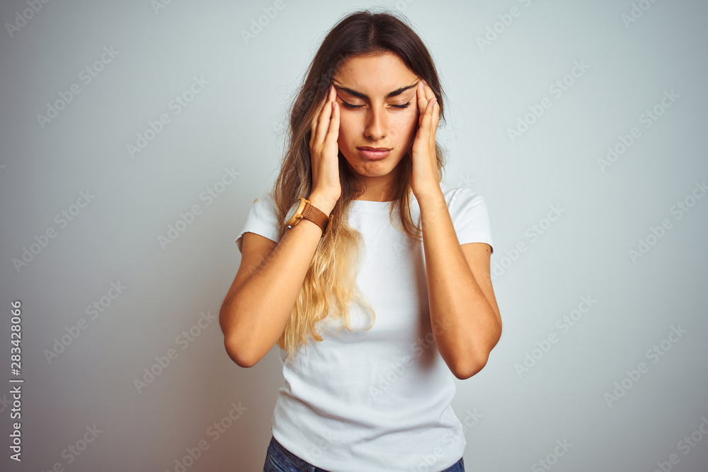 Young beautiful woman wearing casual white t-shirt over isolated background with hand on headache because stress. Suffering migraine. Young beautiful woman wearing casual white t-shirt over isolated background with hand on headache because stress. Suffering migraine.