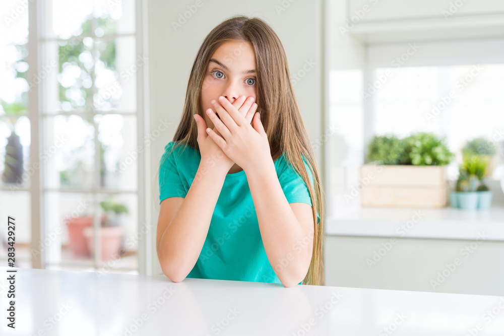 Beautiful young girl kid wearing green t-shirt shocked covering mouth with hands for mistake. Secret concept. Beautiful young girl kid wearing green t-shirt shocked covering mouth with hands for mistake. Secret concept.