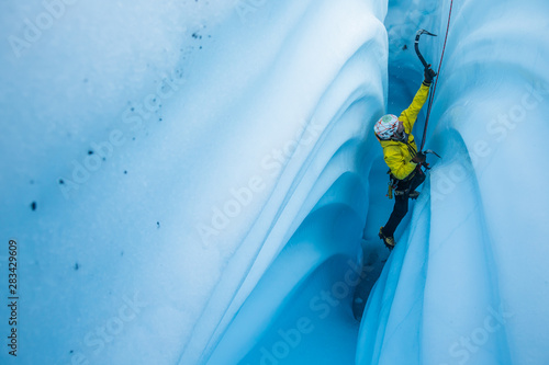 Cuadro en lienzo Narrow canyon of ice with wavy walls and an ice climber ascending the narrow slot