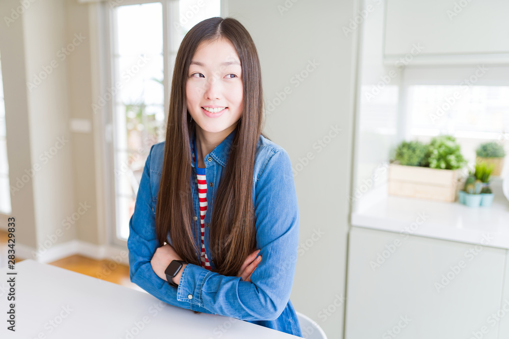 Beautiful Asian woman wearing denim jacket on white table smiling looking side and staring away thinking. Beautiful Asian woman wearing denim jacket on white table smiling looking side and staring away thinking.