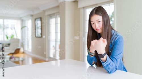 Young beautiful asian woman with long hair wearing denim jacket Ready to fight with fist defense gesture, angry and upset face, afraid of problem