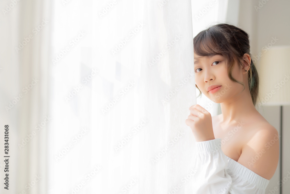 Portrait of beautiful young asian woman standing the window and smile while wake up with sunrise at morning, girl happy with freshness and cheerful, lifestyle and relax concept. Portrait of beautiful young asian woman standing the window and smile while wake up with sunrise at morning, girl happy with freshness and cheerful, lifestyle and relax concept.