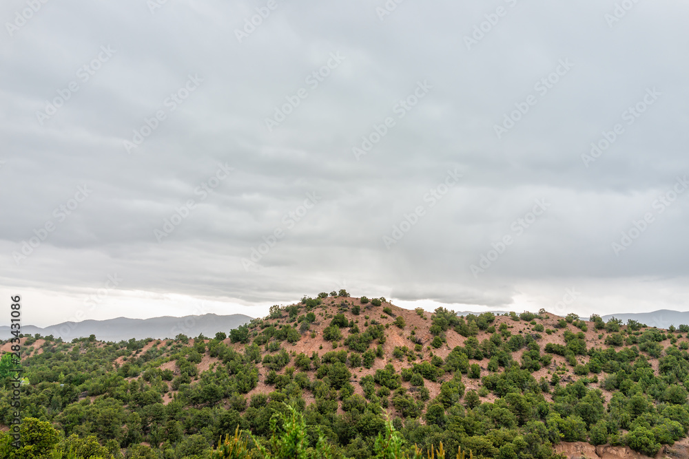 Sunset evening on stormy cloudy overcast day in Santa Fe, New Mexico mountains in Tesuque community neighborhood with green plants