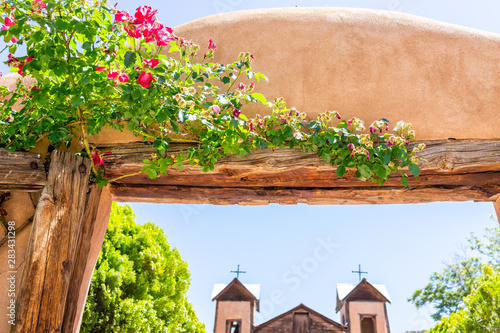 Famous El Santuario de Chimayo sanctuary church in the United States with entrance gate closeup of flowers in summer photo