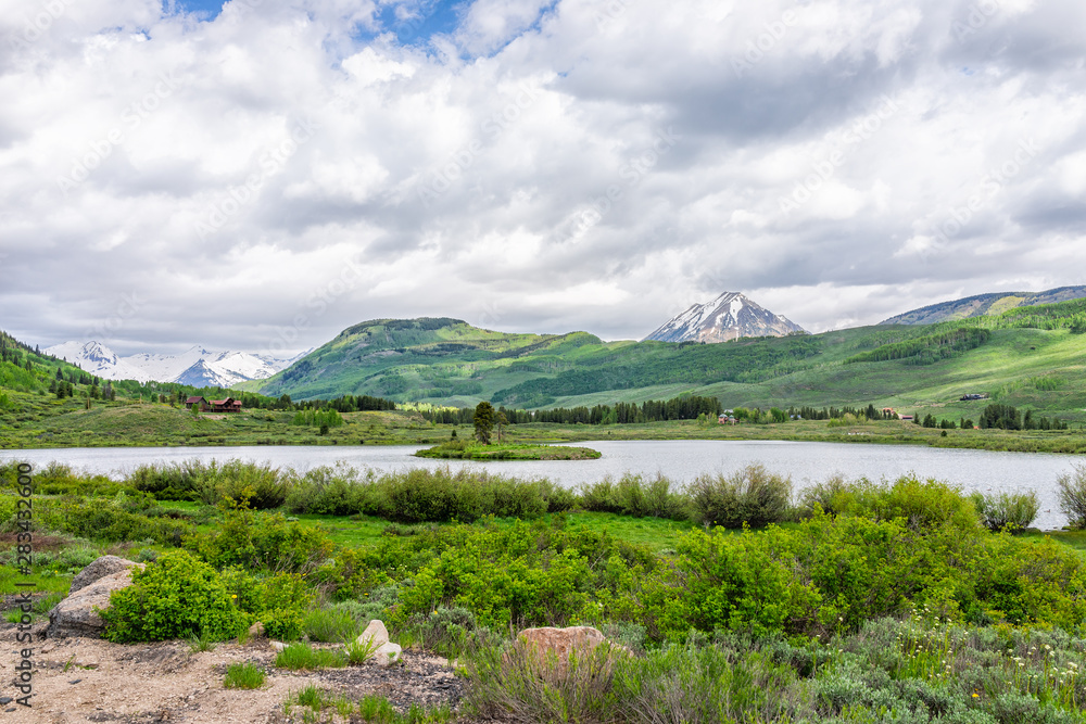 Crested Butte, Colorado alpine peanut lake on hiking trail in summer on cloudy day with green grass and mountain view