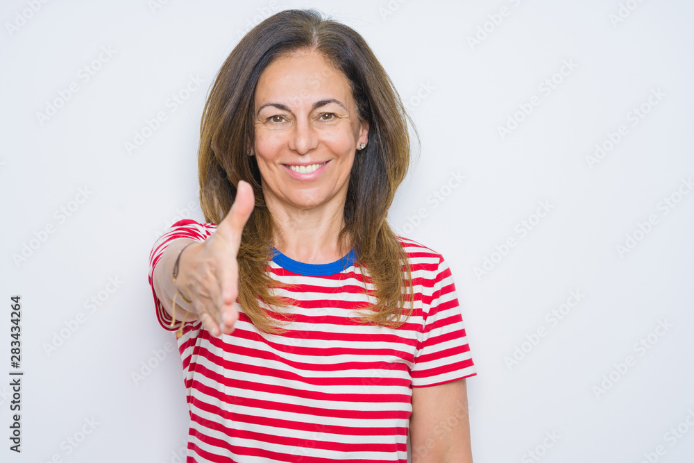 Middle age senior woman standing over white isolated background smiling friendly offering handshake as greeting and welcoming. Successful business. Middle age senior woman standing over white isolated background smiling friendly offering handshake as greeting and welcoming. Successful business.