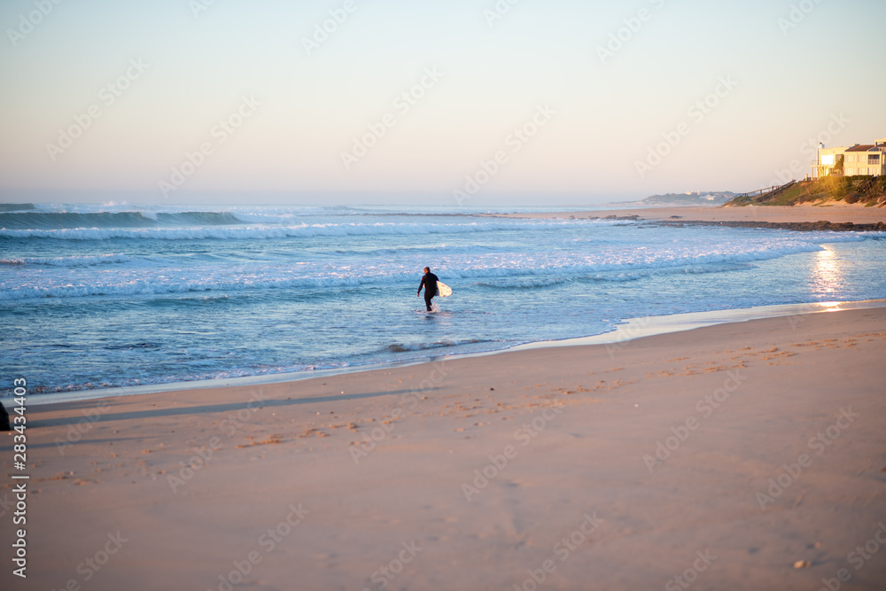 Man heading with his surfboard into the ocean