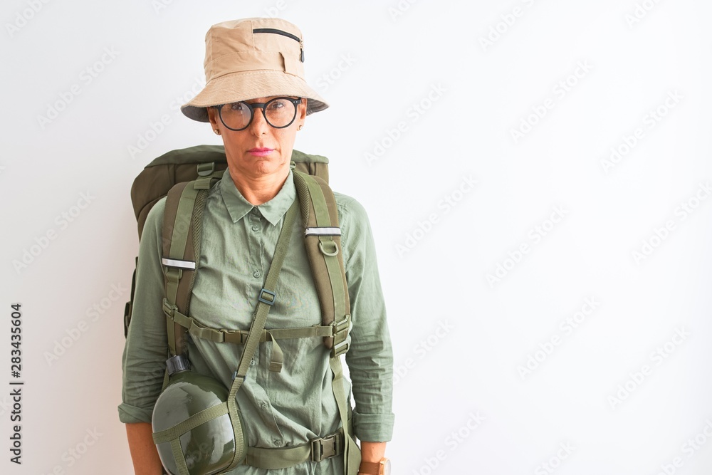 Middle age hiker woman wearing backpack canteen hat glasses over isolated white background skeptic and nervous, frowning upset because of problem. Negative person.