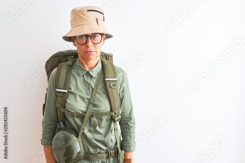 Middle age hiker woman wearing backpack canteen hat glasses over isolated white background skeptic and nervous, frowning upset because of problem. Negative person.