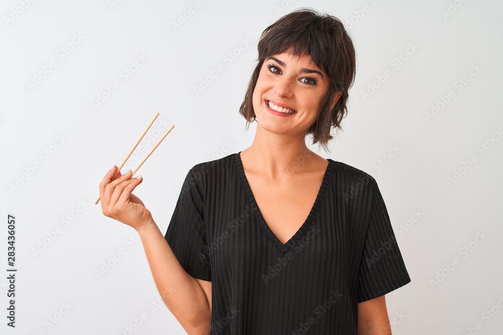 Young beautiful woman holding chopsticks standing over isolated white background with a happy face standing and smiling with a confident smile showing teeth Young beautiful woman holding chopsticks standing over isolated white background with a happy face standing and smiling with a confident smile showing teeth