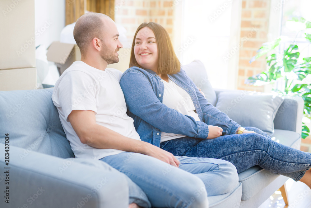Young couple in love relaxing and hugging sitting on the sofa at new home, smiling very happy for moving to a new apartment Young couple in love relaxing and hugging sitting on the sofa at new home, smiling very happy for moving to a new apartment