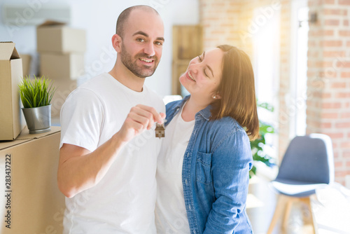 Young couple smiling very happy showing keys of new home, moving and buying new apartmet concept