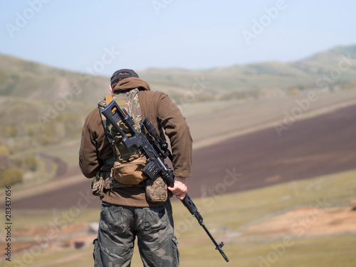 Military man with sniper rifle SVD, view from the back.