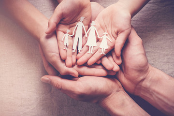 Adult and children hands holding paper family cutout, family home, adoption foster care, homeless charity,family mental health, household budget during inflation