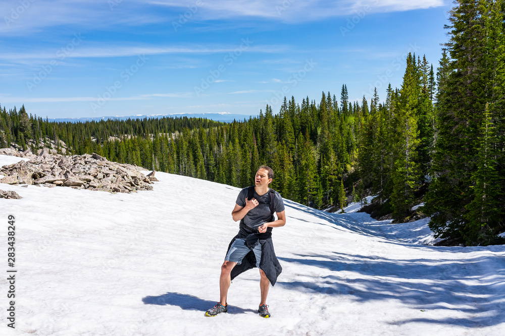 Man climbing summit in Thomas Lakes Hike in Mt Sopris, Carbondale, Colorado tired panting in early 2019 summer with snow on peak