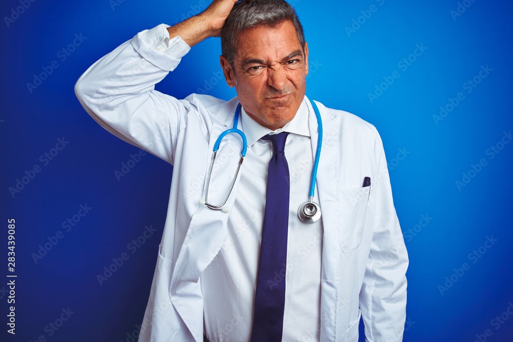 Handsome middle age doctor man wearing stethoscope over isolated blue background confuse and wonder about question. Uncertain with doubt, thinking with hand on head. Pensive concept. Handsome middle age doctor man wearing stethoscope over isolated blue background confuse and wonder about question. Uncertain with doubt, thinking with hand on head. Pensive concept.