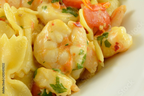 Shrimp and farfalle pasta with tomatoes in white serving dish