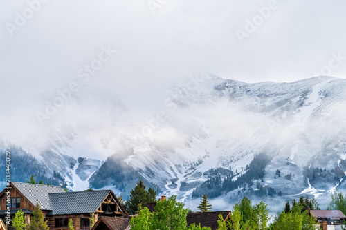 Mount Crested Butte, USA Colorado village in summer with clouds and foggy mist sunrise morning and houses on hills with green trees