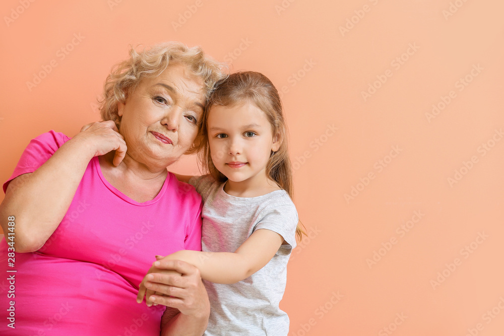 Cute little girl with grandmother on color background Cute little girl with grandmother on color background