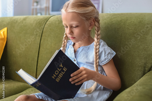 Little girl reading Bible a...