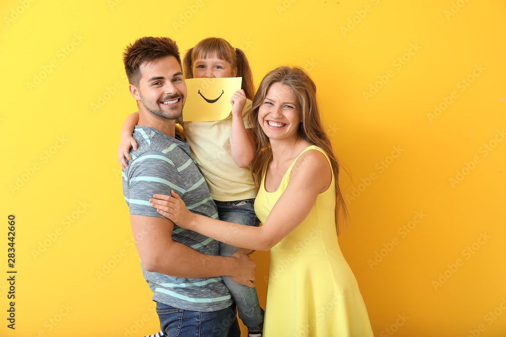 Portrait of happy family with drawn smile on sheet of paper against color background Portrait of happy family with drawn smile on sheet of paper against color background