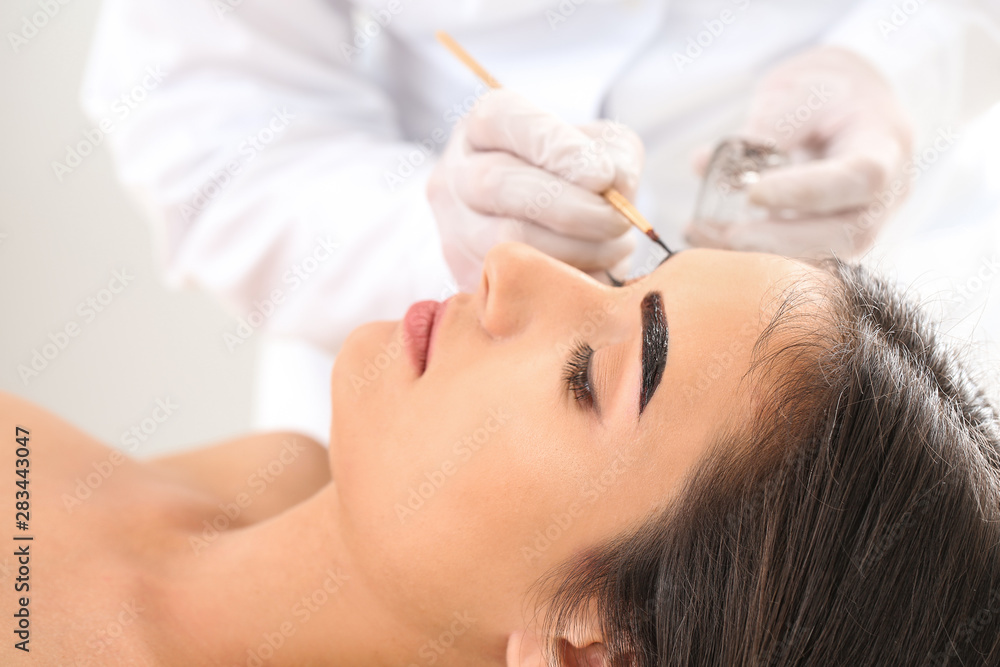 Young woman undergoing eyebrow correction procedure in beauty salon Young woman undergoing eyebrow correction procedure in beauty salon