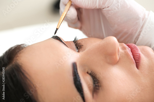 Young woman undergoing eyebrow correction procedure in beauty salon, closeup © Pixel-Shot