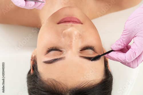 Young woman undergoing eyebrow correction procedure in beauty salon