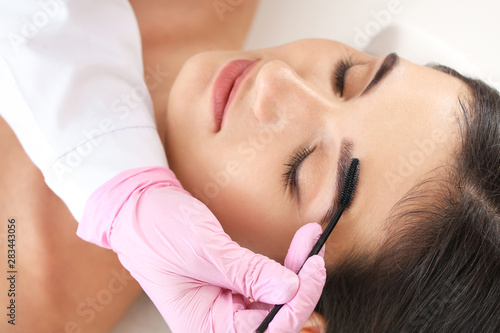 Young woman undergoing eyebrow correction procedure in beauty salon