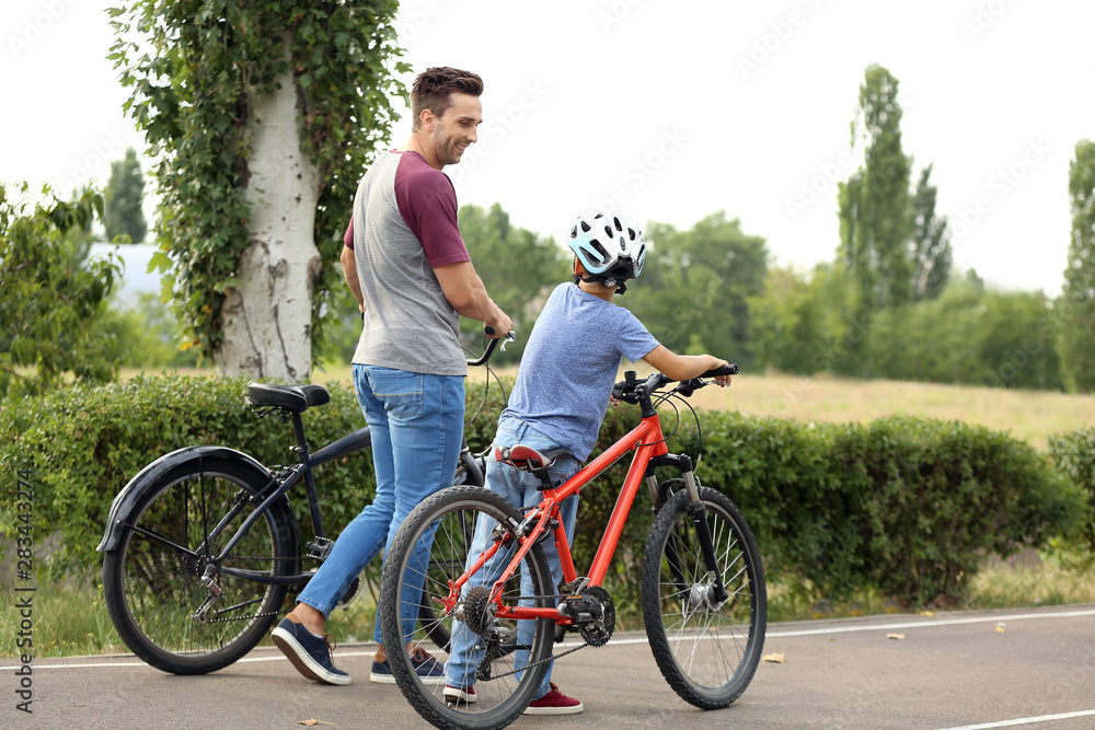 Obraz premium Happy father and son riding bicycles outdoors