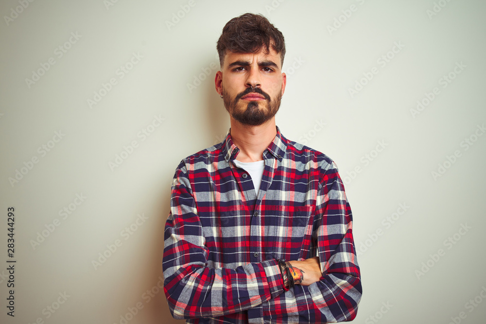 Fototapeta premium Young man wearing casual shirt standing over isolated white background skeptic and nervous, disapproving expression on face with crossed arms. Negative person.