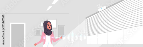 arab woman using smart speaker voice recognition activated digital assistant concept modern living room interior flat horizontal portrait