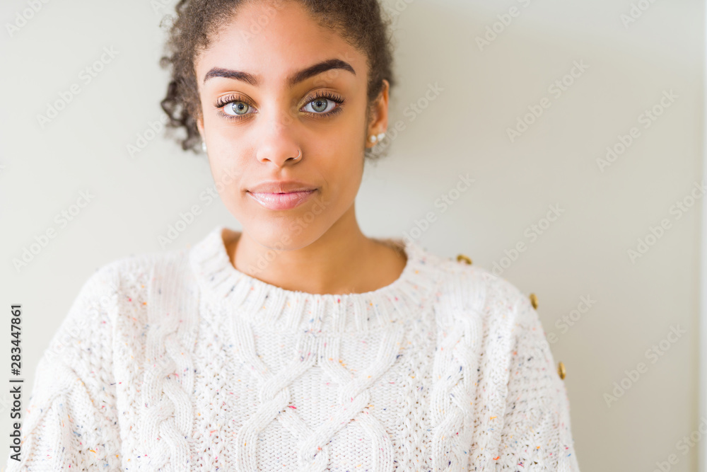 Beautiful young african american woman with afro hair wearing casual sweater Relaxed with serious expression on face. Simple and natural with crossed arms Beautiful young african american woman with afro hair wearing casual sweater Relaxed with serious expression on face. Simple and natural with crossed arms
