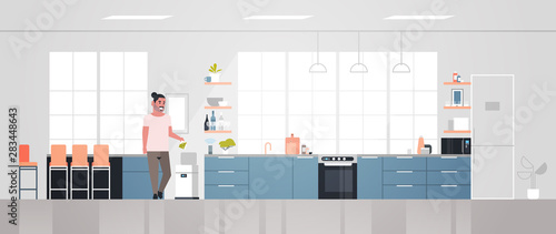 casual man putting trash in electronic recycling bin controlled by smart speaker voice recognition activated digital assistant concept modern kitchen interior horizontal full length