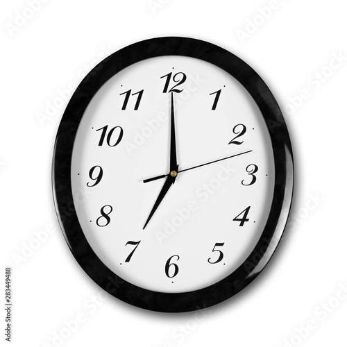Large round white wall clock with black frame. The hands point to 7 o'clock. Close up. Isolated on white background